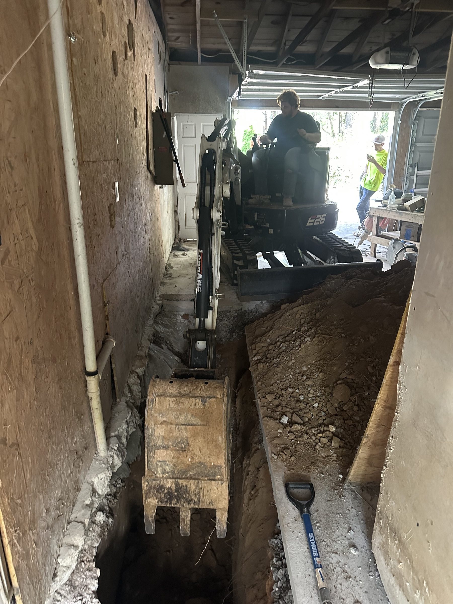 Trench excavation inside a garage with a mini excavator