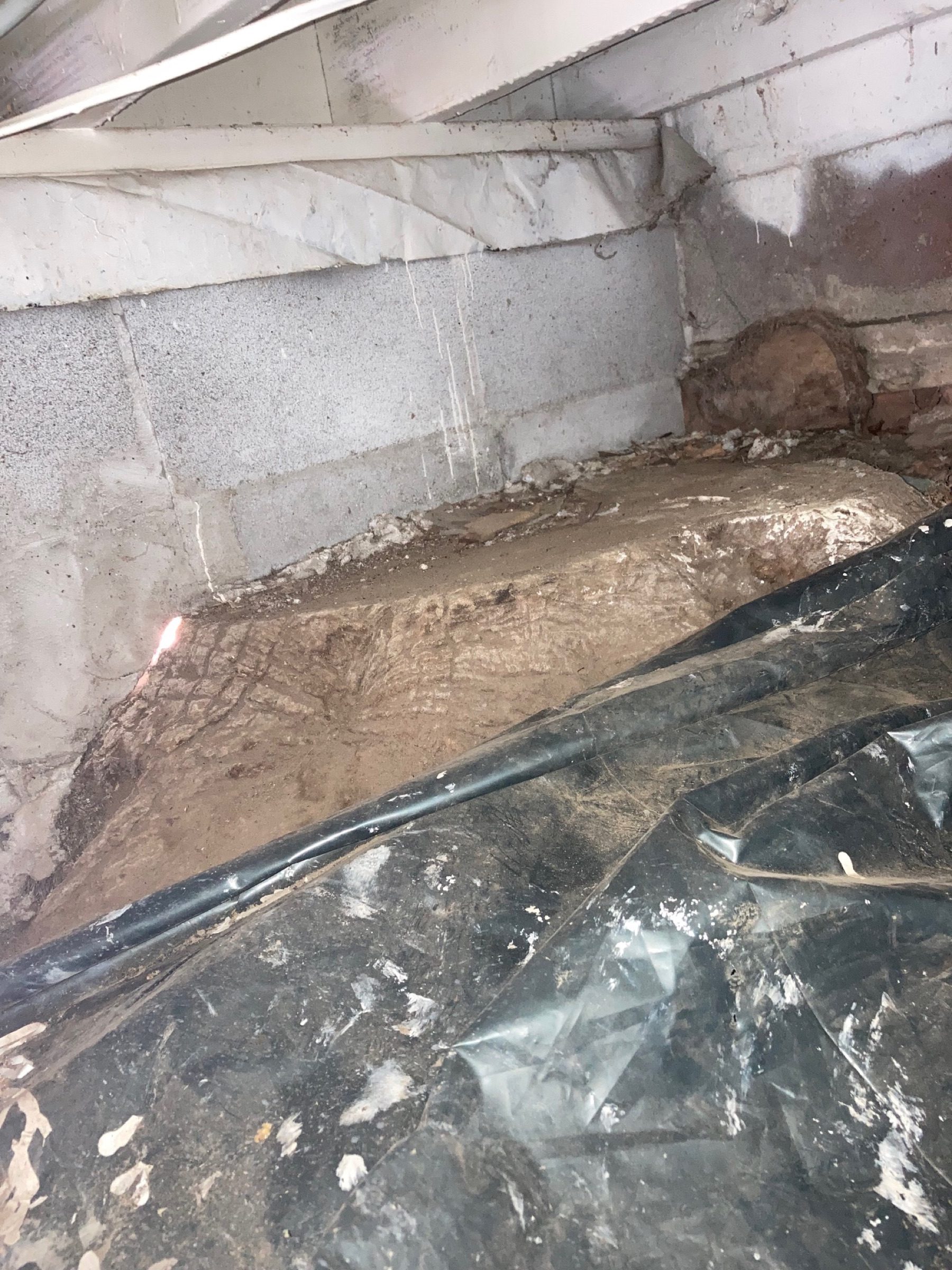 Wet crawlspace with standing moisture over bare ground and loose sheeting